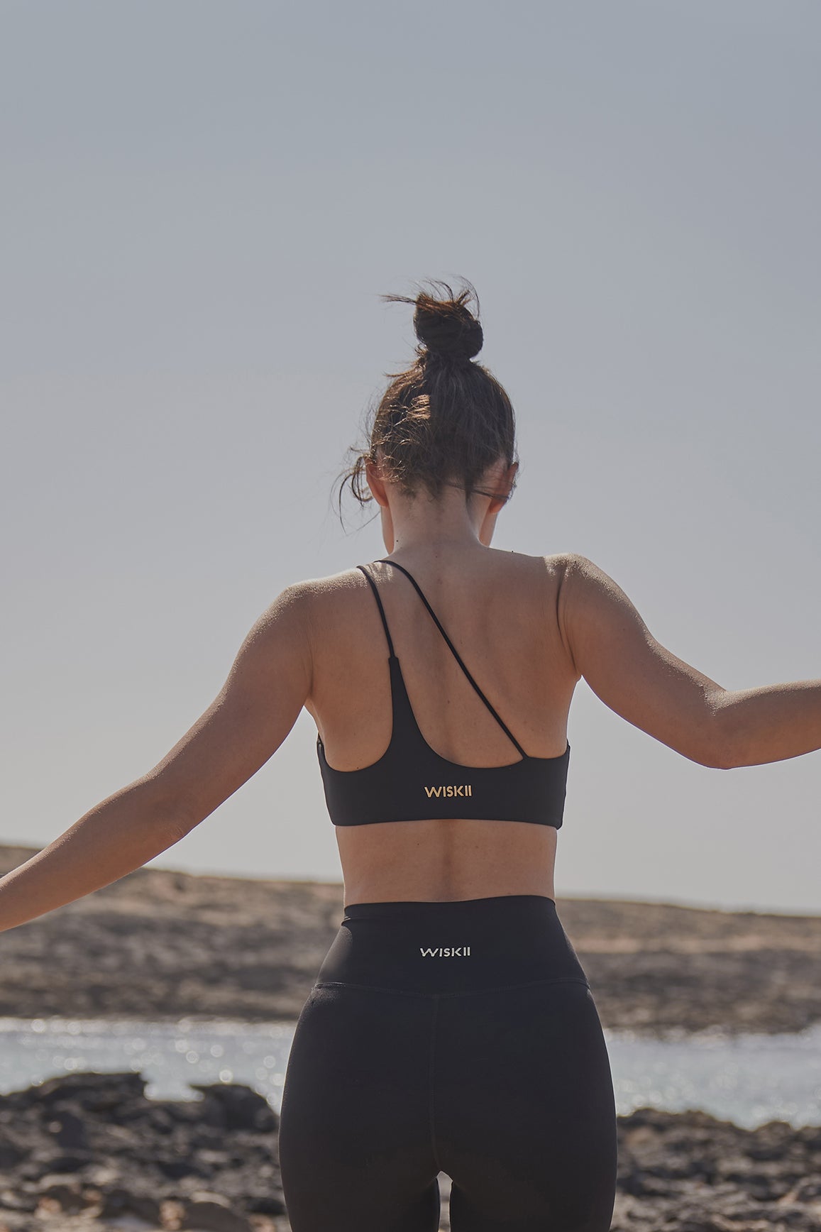 Black WISKII sports bra with one-shoulder contour design, showcasing supportive, seamless athletic wear for active comfort.